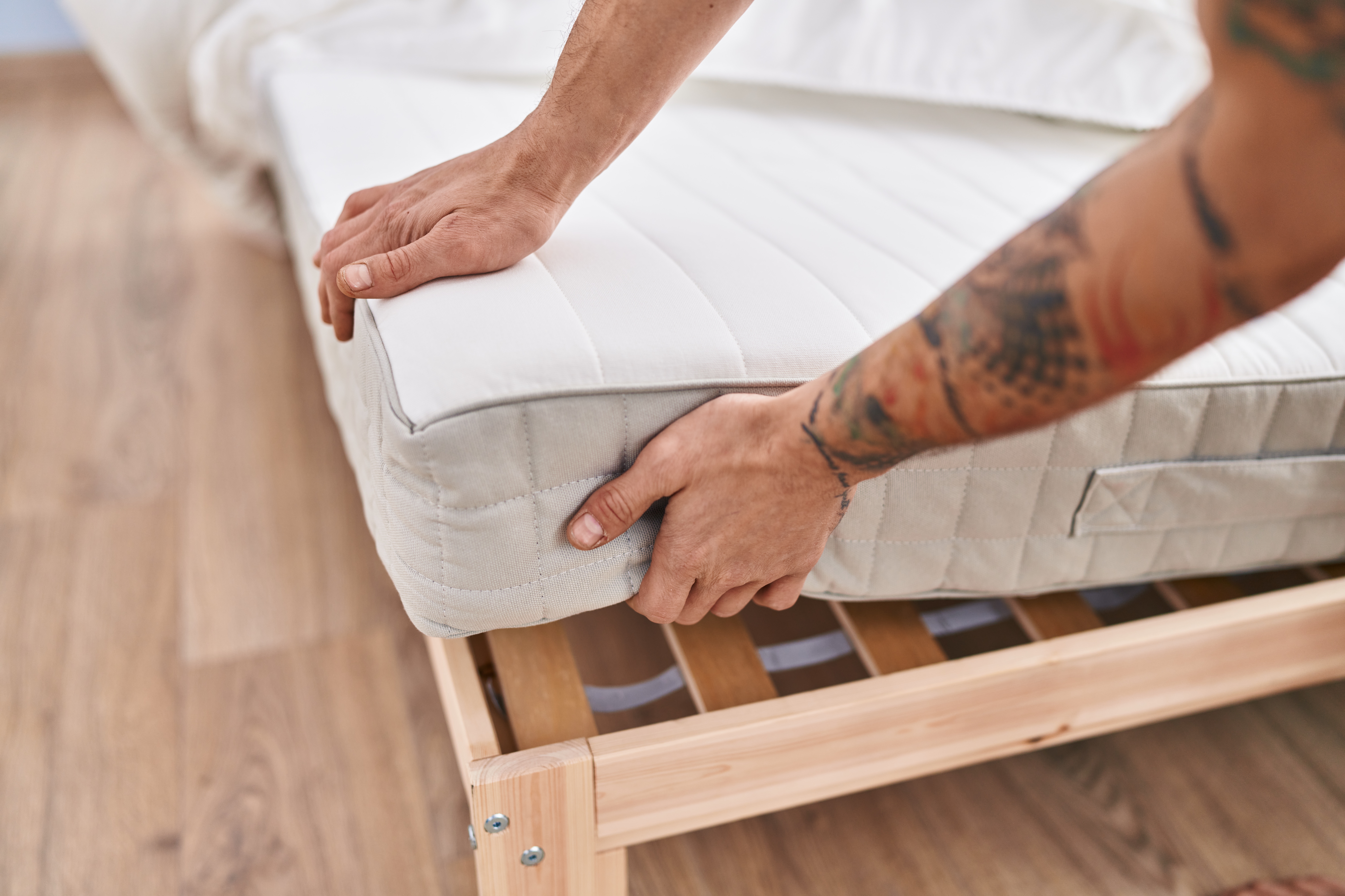 Young man holding mattress at bedroom